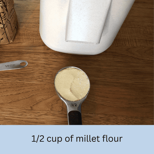 half cup of millet flour in a measuring cup on a wooden countertop