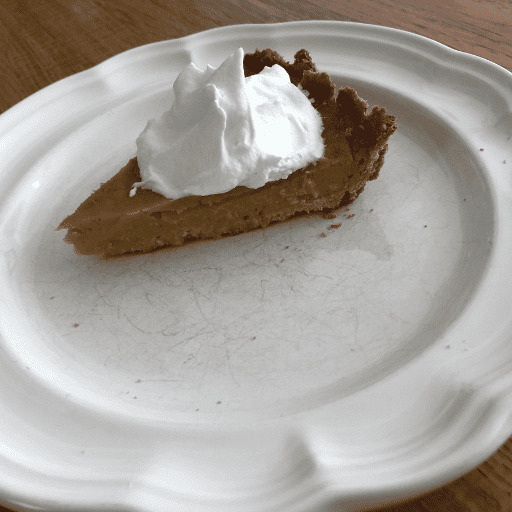 a slice of gluten and dairy free maple pumpkin spice pie served on a white plate with a dollop of whipped cream