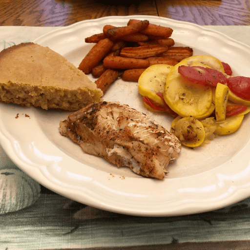 meal of cornbread, fish, carrots, and steamed squash
